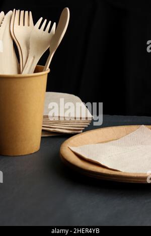 Öko Handwerk Papier Geschirr. Pappbecher, Geschirr und Holzbesteck auf dunklem Hintergrund. Recyclingkonzept. Stockfoto