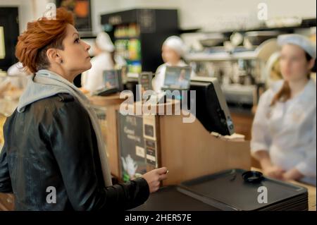 Junge Frau kauft frisches Gebäck auf dem Bäckermarkt auf der Straße. Backwaren Stockfoto