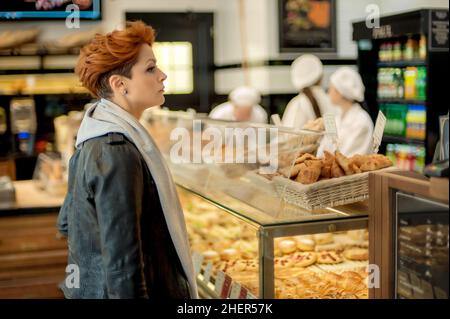 Junge Frau kauft frisches Gebäck auf dem Bäckermarkt auf der Straße. Backwaren Stockfoto