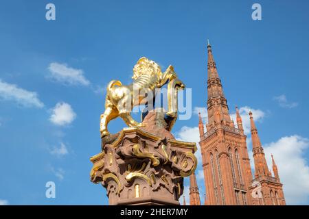 Goldener Nassauer Löwe am Marktbrunnen in Wiesbaden, Deutschland mit Spitze der Marktkirche Stockfoto