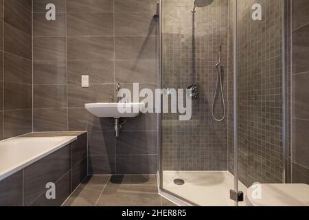 Cowlinge, Suffolk, England - 28. März 2019: Luxuriöse, generische Badsuite mit grauen Fliesen und einer Duschkabine mit Glasfront inklusive Badewanne und Waschbecken Stockfoto