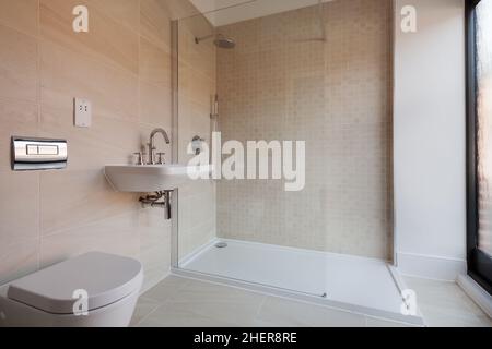 Cowlinge, Suffolk, England - 28. März 2019: Luxus-Bad-Suite mit gefliesten Wänden und bodenverglaster Duschkabine, Waschbecken, Toilette und WC. Stockfoto