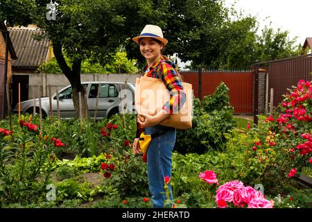 Junge Frau mit Öko-Tragetasche oder Shopper auf der Schulter und lächelnd. Öko-Beutel, Kunststoff stoppen. Natur Sommer Hintergrund, Hinterhof. Stofftasche aus Baumwolle Stockfoto