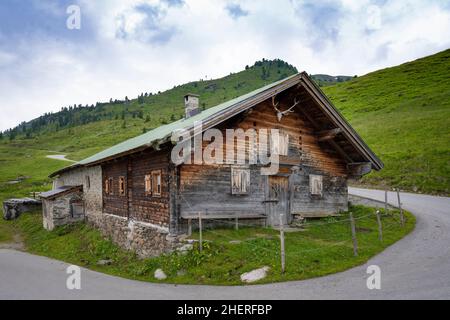 Altes Holz- und Steinhaus in österreichischen Bergen mit Hirschgeweih unter dem Bergrücken Stockfoto