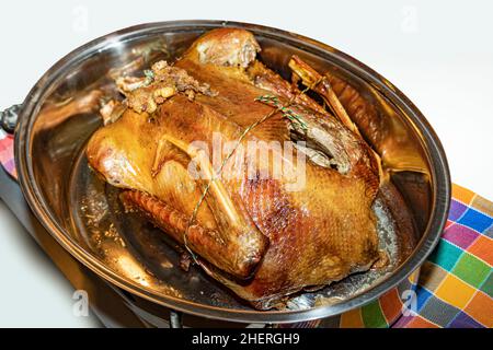 Gebratene gefüllte Gans auf dem Teller mit reifen Äpfeln über dem hölzernen Küchentisch. Draufsicht. Stockfoto