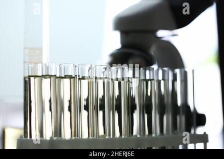 Glasröhrchen mit gelber Flüssigkeit auf dem Mikroskop Stockfoto