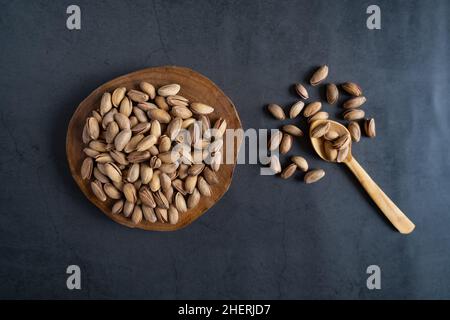 Pistazien auf Servierbrett. Geröstete und geschälte Pistazien auf Beton, Steingrund. Flach liegend, Draufsicht. Gesunde, leckere Snacks. Stockfoto