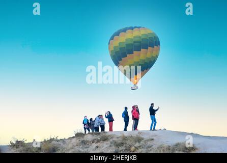 Heißluftballon fliegt und Touristen genießen Moment in Kappadokien, Türkei. Fliegen mit einem Heißluftballon ist eine beliebte Aktivität in Kappadokien, Türkei. Stockfoto