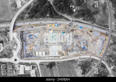 Vogelperspektive von oben auf große Baustelle mit Turmkräne umgeben von Straßen Stockfoto