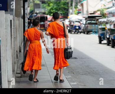 Zwei junge Mönche, die in Bangkok eine Straße entlang gehen. Rückansicht. Stockfoto