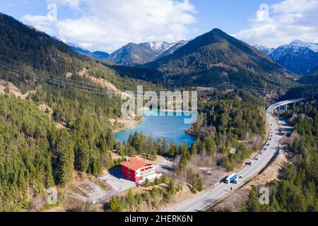 urisee neben Autobahn mit Hotel in österreichischen Bergen im Frühling Stockfoto