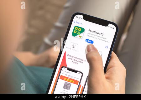 Charkow, Ukraine - 10. Januar 2022: PassCovidTG App Icon Nahaufnahme. Frau mit Anwendung auf dem Apple iPhone 12 Stockfoto