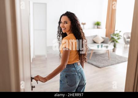 Rückansicht einer aufgeregt jungen Frau, die in der Wohnung läuft Stockfoto