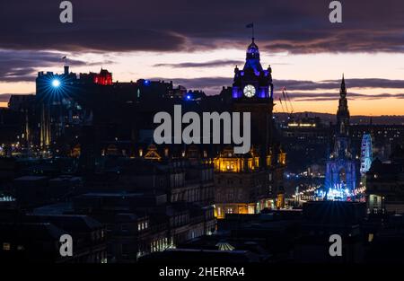 Eine Lichtshow vom Edinburgh Castle über der Skyline der Stadt mit einem farbenfrohen orangefarbenen Sonnenuntergang und weihnachtlichen festlichen Lichtern, Edinburgh, Schottland, Großbritannien Stockfoto