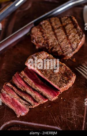 Gegrilltes saftiges Steak auf einem Schneidebrett. Mittelseltenes Rindersteak-Fleisch auf einem Schneidebrett Stockfoto
