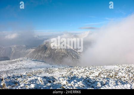 Der Englische Lake District. Wolken strömen von einem verschneiten Gable. Stockfoto