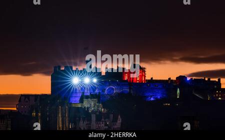 Eine Lichtshow vom Edinburgh Castle über der Skyline der Stadt mit einem farbenfrohen orangefarbenen Sonnenuntergang, Edinburgh, Schottland, Großbritannien Stockfoto