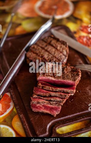 Köstliches saftiges gegrilltes Rindersteak auf einem Schneidebrett. Zartes Rindfleisch in Scheiben geschnitten. Geringe Schärfentiefe Stockfoto