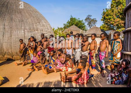 Kinder beobachten mit Interesse die traditionellen Bräuche in einem echten afrikanischen Dorf, Umphakatsi Chief Stockfoto