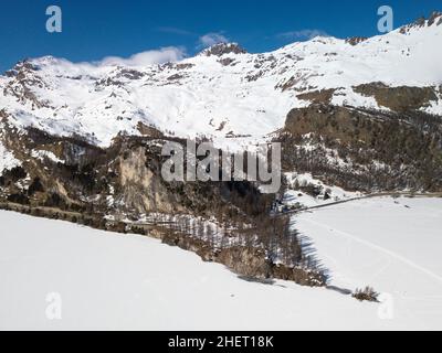 Luftaufnahme einer Inselspitze auf einem gefrorenen See mit Schnee, der die gefrorene Seenoberfläche bedeckt, und Loipen zum Skilanglauf und Wandern. Stockfoto