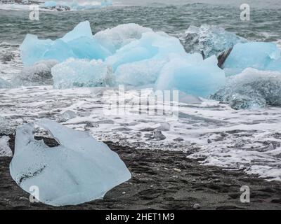 Während des Sonnenuntergangs funkeln unglaubliche Teile des Eisbergs am berühmten Diamond Beach in der Jokulsarlon Lagune Stockfoto