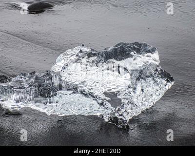 Während des Sonnenuntergangs funkeln unglaubliche Teile des Eisbergs am berühmten Diamond Beach in der Jokulsarlon Lagune Stockfoto