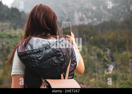 Allein weibliche Touristen in vesta und Rucksack, die ein Foto auf dem Smartphone von erstaunlichen Bergkette in der Hohen Tatra in der Slowakei. Wandern im Sommer Konzept. Die Schönheit der Natur Stockfoto
