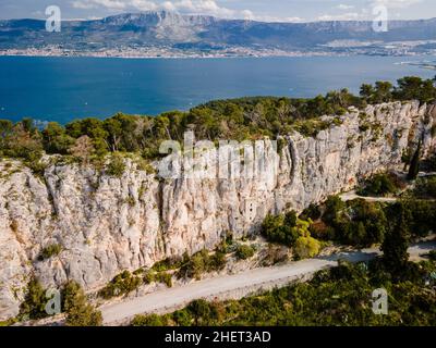 Altes historisches Gebäude mit dem Turm von Karepica. Kirche in Wall, Split, Kroatien. Im Hintergrund Ozean und Berge. Stockfoto