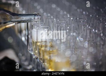 Champagner, der Gläser aus einer Flasche eingießt. Spritzer und Tropfen. Konzept für den Urlaub. Stockfoto