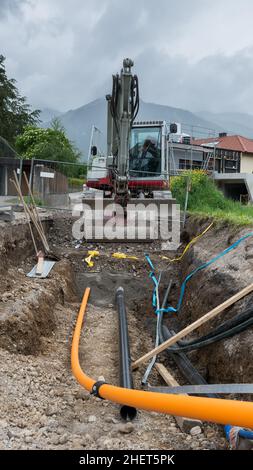 Schaufelbagger graben Gas- und Stromleitungen unter der Straße Stockfoto