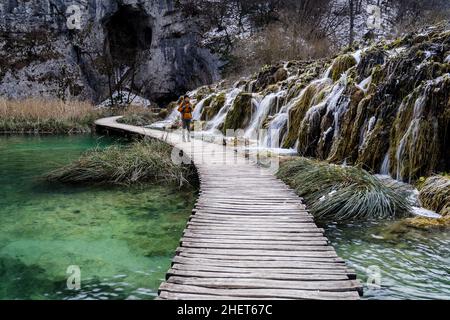 Frauen wandern rustikale Holzpromenade mit kleinen Wasserfällen im Nationalpark Plitvicer Seen, Kroatien Stockfoto