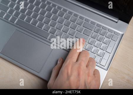 Hand auf Laptop-Tastatur, Tippen und Drücken der Taste mit Finger Nahaufnahme. Stockfoto