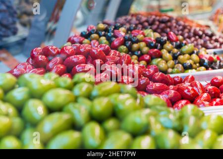 Viel frisches Grün, Rot und gemischte Oliven auf dem Markt Stockfoto