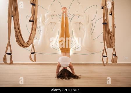 Rückansicht eines passgenau gedrehten aportswoman, der im Yoga-Studio ein Shirshasana-Kopfstand macht Stockfoto