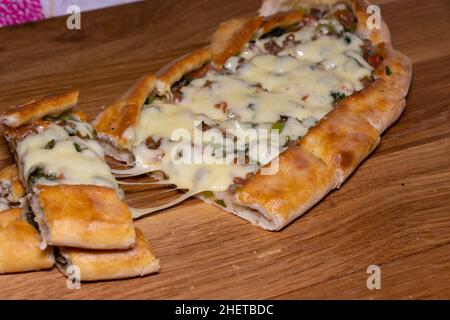 Türkische Pita mit Rindfleisch und Käse. Türkisches Pide mit Fleischkäse und Gemüse auf einem hölzernen Hintergrund Stockfoto