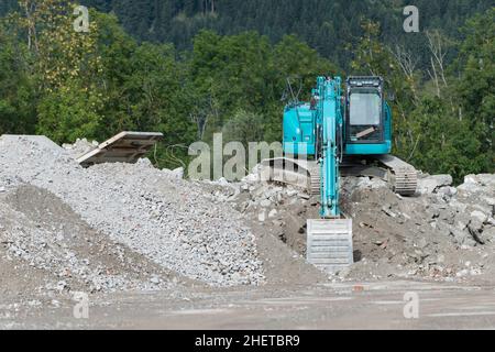 Blauer Schaufelgräber auf Schotterhaufen vor dem Wald Stockfoto