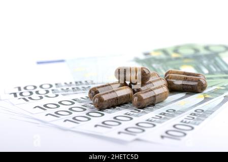 Nahaufnahme einer Gruppe von Nahrungsergänzungsmitteln oder Vitamintabletten auf entkochten hundert-Euro-Banknoten. Das Konzept der hohen Kosten von Medikamenten. Stockfoto