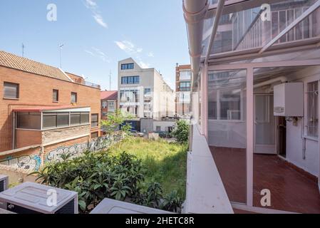 Verglaste Terrasse mit Blick auf den Innenbereich mit Pflanzen und hohem Gras Stockfoto