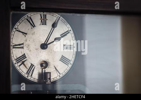 alte Retro-Uhr mit römischen Ziffern hinter Glas Stockfoto