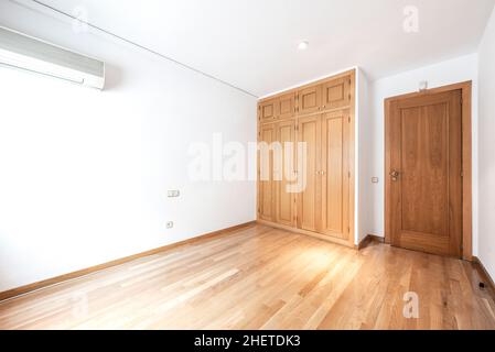 Leeres Zimmer mit eingebautem Eichenschrank und Eichenparkettböden mit Klimaanlage. Stockfoto