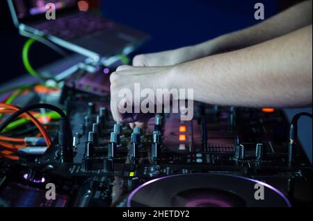 Nahaufnahme des DJ Mixer Controller Desk bei der Night Club Disco Party. DJ Hände berühren Tasten und Schieberegler spielen elektronische Musik . Hochwertige Fotografie. Stockfoto