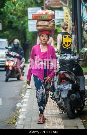 BALI, INDONESIEN - 14. APRIL 2018. Balinesische Frau mit Korb auf dem Kopf gehen zum Tempelfest. Redaktionelle Tagesaufnahme Stockfoto