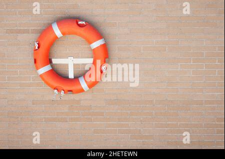 Roter Rettungsring an einer Ziegelwand eingehängt Stockfoto
