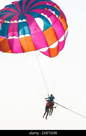 PHUKET, THAILAND - 13. MÄRZ 2018. Paar mit dem Instruktor, der mit dem Fallschirm über den klaren Himmel fliegt. Redaktionelle Tagesaufnahme Stockfoto