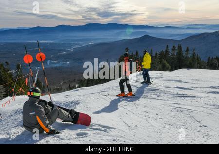 Snowboarder und Skifahrer, die sich bereit machen, die Piste vom Gipfel des Peak Mansfield Summit im Stowe Vermont Mountain Resort aus hinunterzufahren. Schöner Wintertag Stockfoto