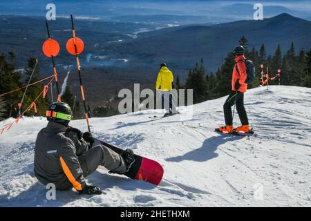 Snowboarder und Skifahrer, die sich bereit machen, die Piste vom Gipfel des Peak Mansfield Summit im Stowe Vermont Mountain Resort aus hinunterzufahren. Schöner Wintertag Stockfoto