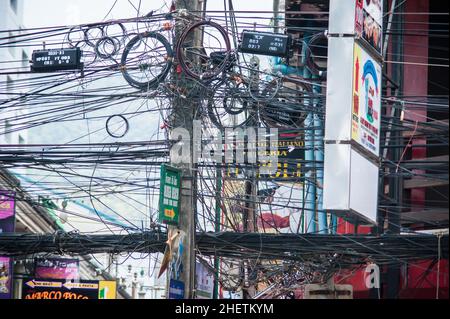 PHUKET, THAILAND - 13. MÄRZ 2018. Lampenpfosten auf Gewirr von elektrischen Drähten Hintergrund. Redaktionelle Tagesaufnahme Stockfoto