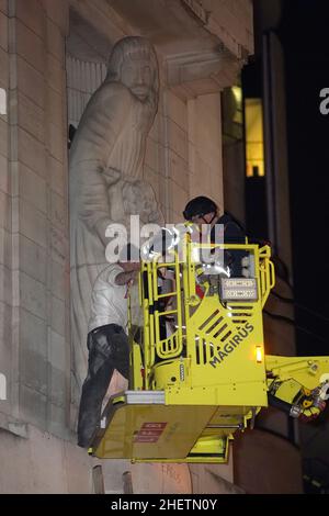 Ein Mann wird auf den Feuerwehrzug gebracht, nachdem er auf die Statuen Prospero und Ariel aus Shakespeares Theaterstück The Tempest des Bildhauers Eric Gill vor dem BBC-Hauptquartier im Zentrum von London geklettert und mit Hammer geschlagen hat. Die Metropolitan Police sagte, dass am Mittwoch gegen 4,15pm Uhr Beamte zum Broadcasting House in der Portland Street, Westminster, gerufen wurden, wo ein Mann eine Leiter benutzt hatte, um die 10 Meter hohen Figuren über dem Vordereingang zu erreichen. Bilddatum: Mittwoch, 12. Januar 2022. Stockfoto