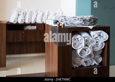 Weiße Handtücher und Bademäntel, sortiert auf Holzschränken und Regalen Stockfoto
