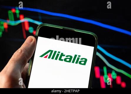 China. 09th Dez 2021. In dieser Abbildung sehen Sie das Logo der italienischen Fluggesellschaft Alitalia, das auf einem Smartphone mit einem Index der wirtschaftlichen Börse im Hintergrund angezeigt wird. (Foto von Budrul Chukrut/SOPA Images/Sipa USA) Quelle: SIPA USA/Alamy Live News Stockfoto